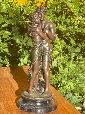une statue représentant un homme et une femme enlacés, posée sur une table