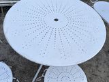 a white table with four chairs and a bench in the background