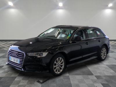 L'Audi break noire est garée dans une grande pièce au sol carrelé en damier.