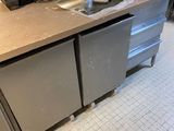 une photo d'une cuisine équipée d'appareils électroménagers et de plans de travail en acier inoxydable