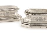 pair of silver candlesticks with engraved designs on the sides
