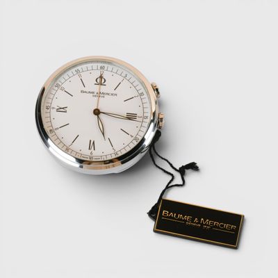 une image représentant une montre de poche en argent et en or, sur laquelle est accrochée une étiquette