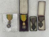 three medals and a ribbon in a case on a white surface