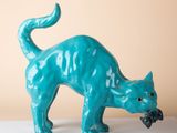 une figurine de chat bleu posée sur une surface blanche