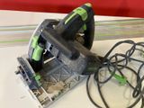 a green and black circular saw on a white table