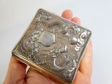 someone is holding a silver box with a dragon design on it