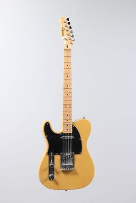 an electric guitar hanging from a string on a wall