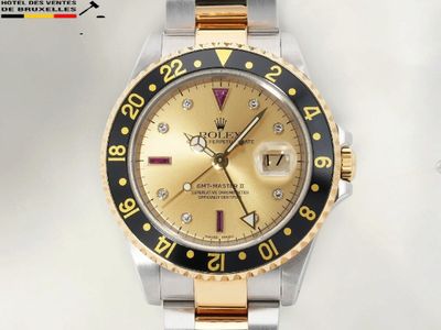 une montre Rolex dorée et noire posée sur une surface blanche