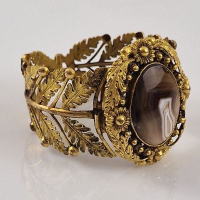 gold bracelet with a large stone surrounded by leaves and flowers