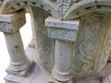 a white marble table with columns and a vase on it
