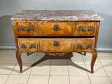 une commode au plateau en marbre posée sur un sol carrelé