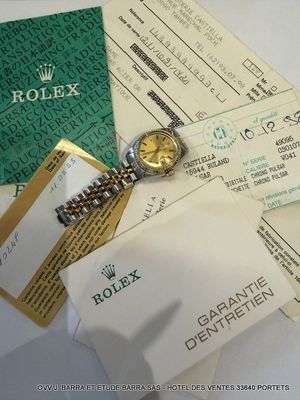 a rolex watch sitting on top of a pile of papers