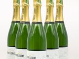 quatre bouteilles de champagne sont alignées sur une surface blanche