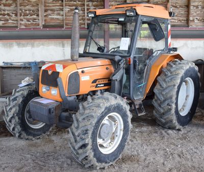 an orange tractor that is parked in the dirt