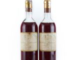 deux bouteilles de vin posées l'une à côté de l'autre sur une surface blanche