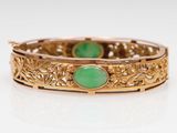 a close up of a gold bracelet with a green stone
