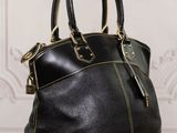 black leather handbag sitting on a wooden table in front of a white wall