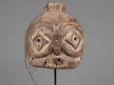 a close up of a wooden mask on a metal stand