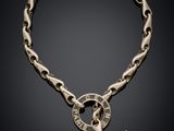 a close up of a chain bracelet with a cross on it