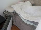 a bed with a blanket on top of it next to a heater