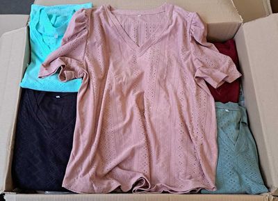une boîte en carton posée par terre et contenant des vêtements