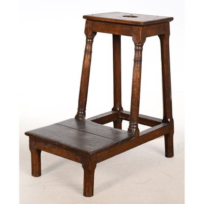 un vieux tabouret en bois posé sur un sol blanc