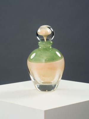 une bouteille en verre contenant un liquide vert, posée sur une surface blanche