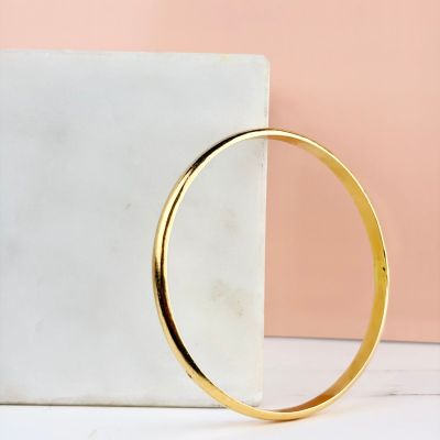 a close up of a gold bang bracelet on a marble block