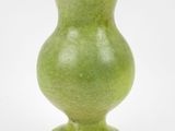 un vase vert posé sur une surface blanche