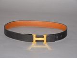 a close up of a black and orange belt with a gold h buckle