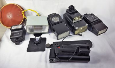 de nombreux types différents d'appareils photo et de flashs posés sur un lit