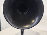 a black hornphone on a wooden stand on a white table