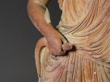 an old statue of a woman holding a flower in her right hand