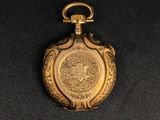 a gold pocket watch with a medallion on the front