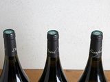 three bottles of wine are lined up on a wooden table