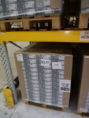Les cartons sont empilés sur des palettes dans un entrepôt et sont munis d'une étiquette de prix.