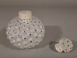 a white vase with black dots on it next to a small white object