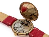 a watch that is sitting on a red leather strap