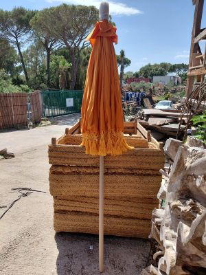an orange umbrella that is on top of a pile of straw