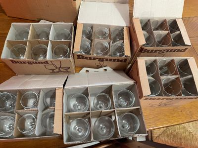 des cartons de verres à vin vides posés sur une table, à côté d'un carton de verres à vin vides