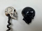 a bottle opener with a skull head on it next to a corkscrew