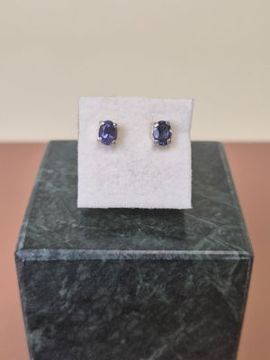 a pair of blue sapphire earrings sitting on top of a marble block