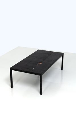 La table est en marbre noir et possède une structure en métal noir.