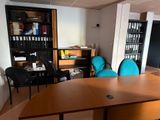 tables and chairs in an office with bookshelves and a bookcase
