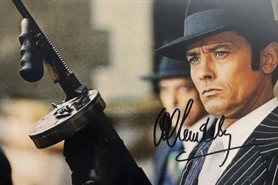 l'image d'un homme en costume et chapeau, tenant un pistolet
