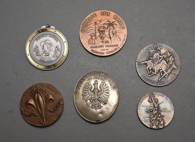 several different coins are shown on a table with a pocket watch
