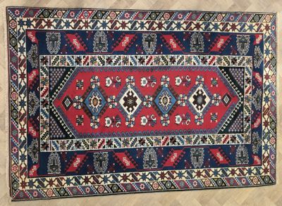 a red, blue and black rug sitting on top of a wooden floor