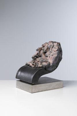 un gros plan d'une sculpture représentant un rocher posé sur un socle métallique