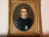 portrait d'un jeune garçon vêtu d'un pull noir et d'une chemise blanche à col