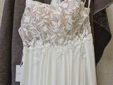 wedding dress hanging on a hanger in front of a white wall
